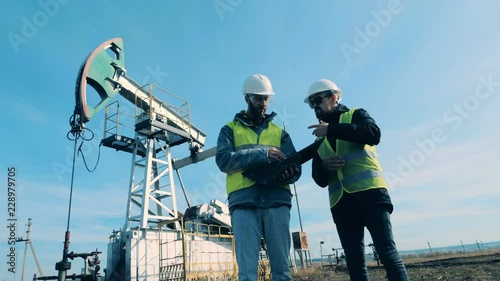 Wallpaper Mural People discussing work near oil towers, close up. Oil industry concept. Torontodigital.ca