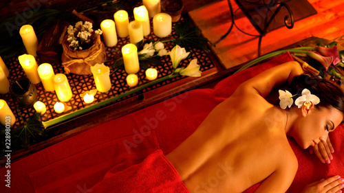 Massage of woman in ayurveda spa salon. Top view of Filipino girl on candles background therapy room. Luxary interior in oriental therapy salon.