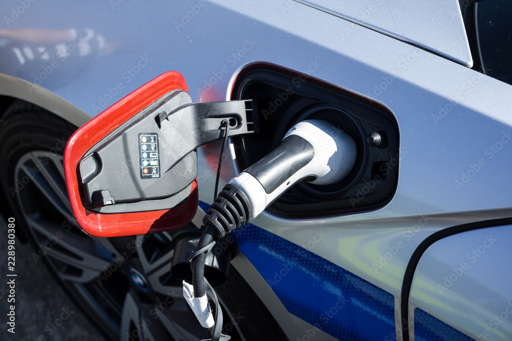 Electric vehicle is plugged into electricity. Battery in car and auto is recharged. Electric green energy as source of energy for transportation