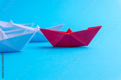 White and red paper ship in one direction on blue background. Business for innovative solution concept with selective focus