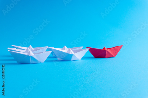 White and red paper ship in one direction on blue background. Business for innovative solution concept with selective focus