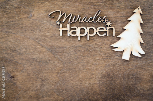 Inscription miracles happen on a wooden background. Concept of inspiration and hope.