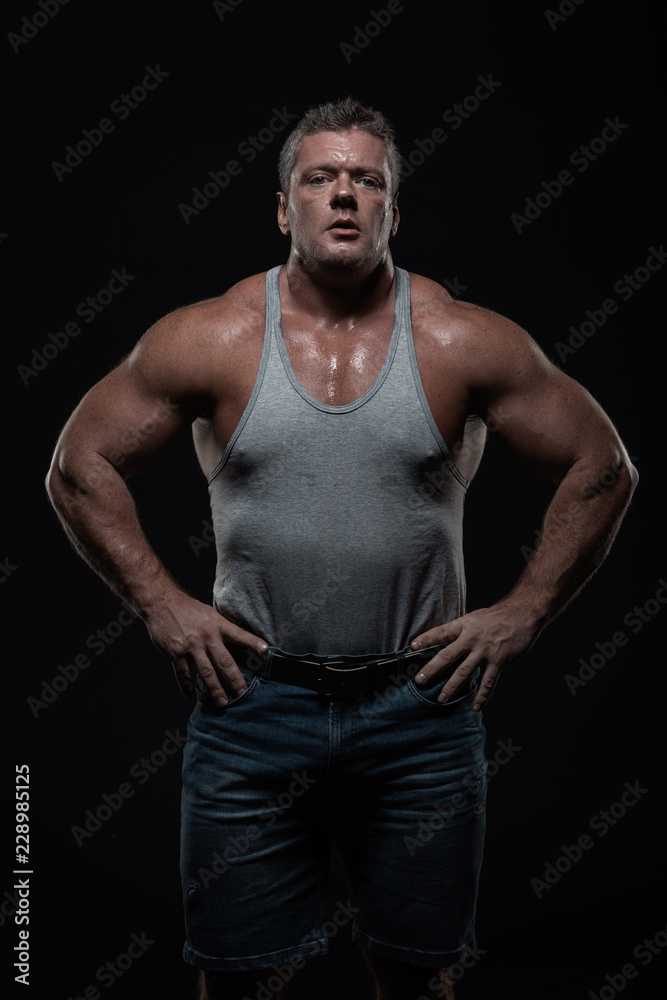 Fototapeta premium Powerful muscular bodybuilder posing on a black background. concept of strength and health