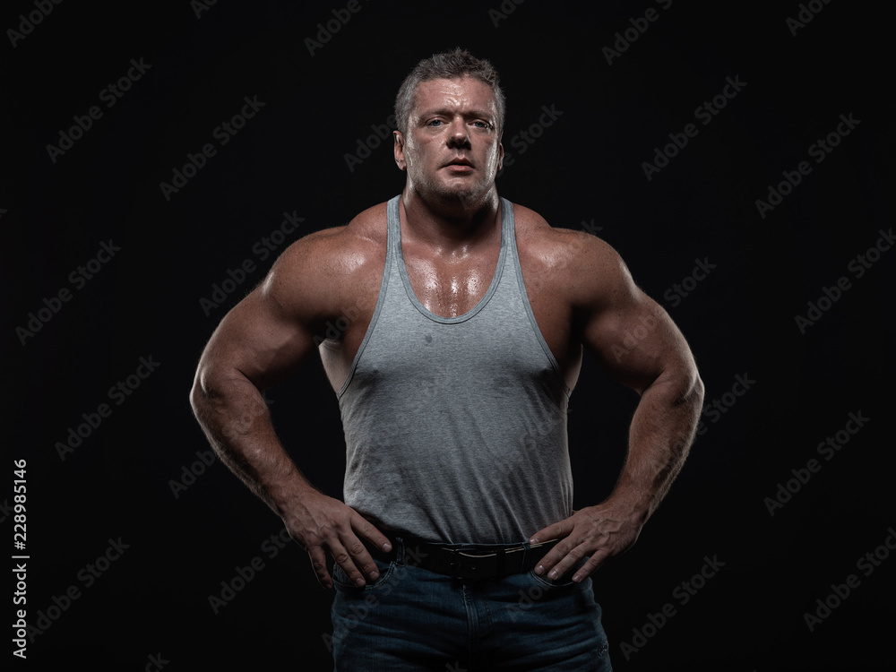 Powerful muscular bodybuilder posing on a black background. concept of strength and health Powerful muscular bodybuilder posing on a black background. concept of strength and health