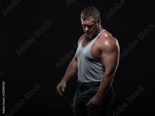 Powerful muscular bodybuilder posing on a black background. concept of strength and health © Vladimir