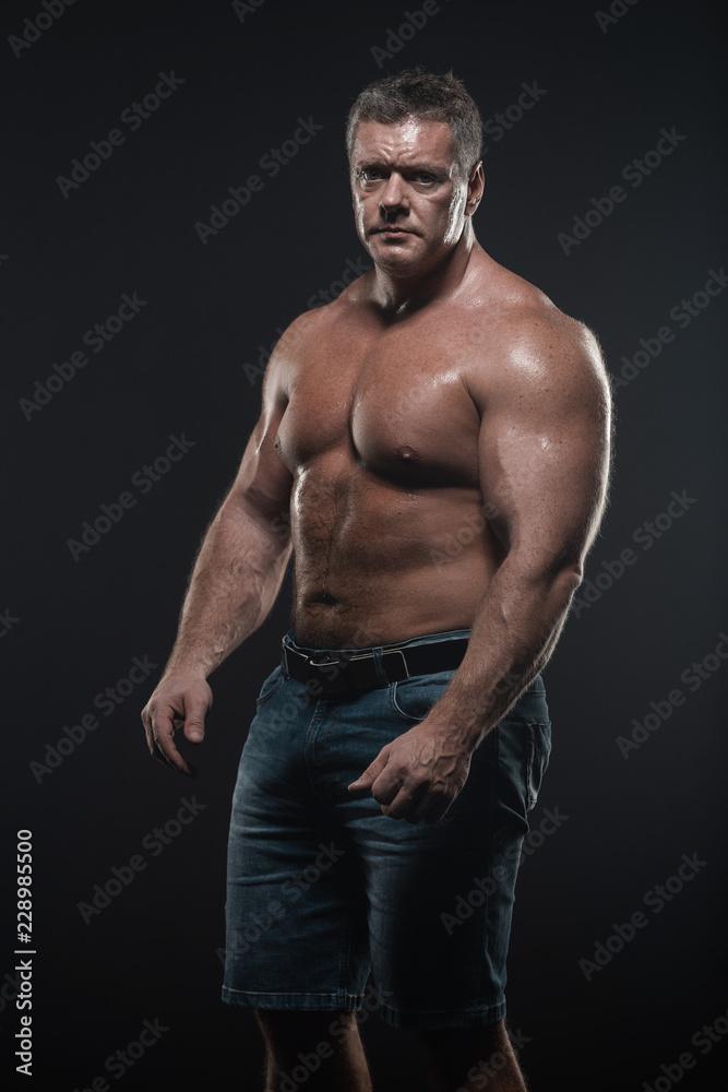 Powerful muscular bodybuilder posing on a black background. concept of strength and health Powerful muscular bodybuilder posing on a black background. concept of strength and health