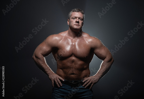 Powerful muscular bodybuilder posing on a black background. concept of strength and health