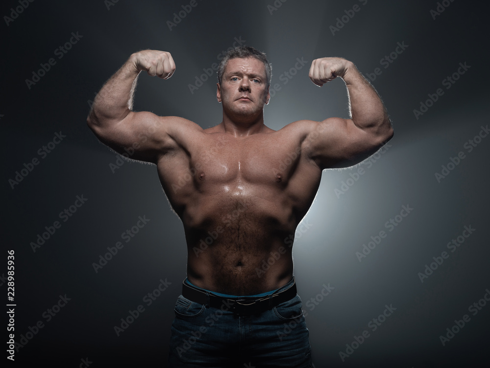 Powerful muscular bodybuilder posing on a black background. concept of strength and health Powerful muscular bodybuilder posing on a black background. concept of strength and health