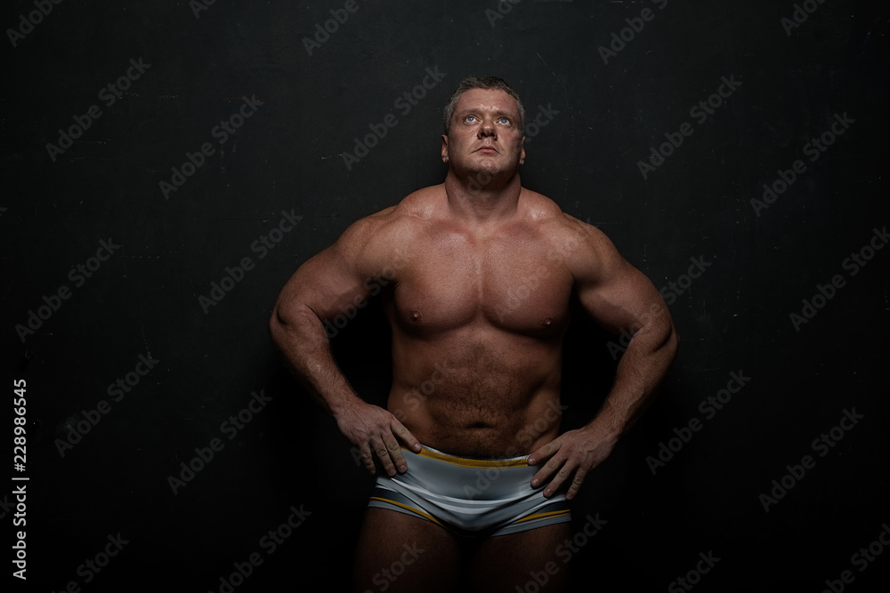 muscular man shows off his body near black grunge wall