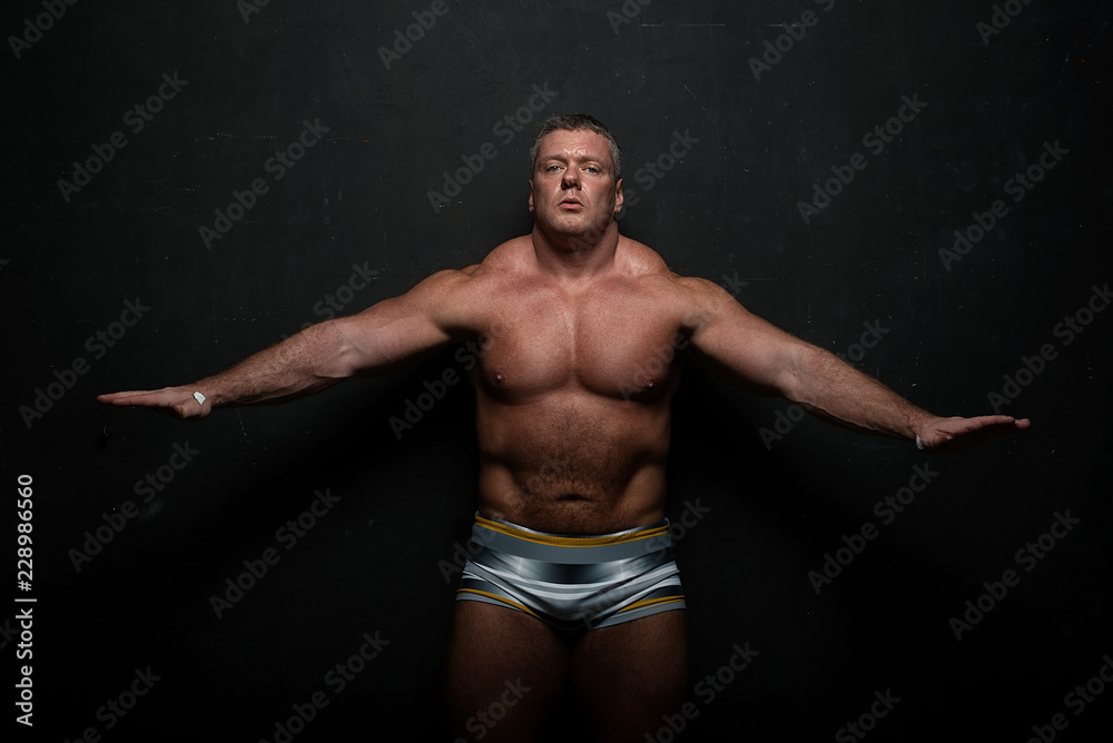 muscular man shows off his body near black grunge wall