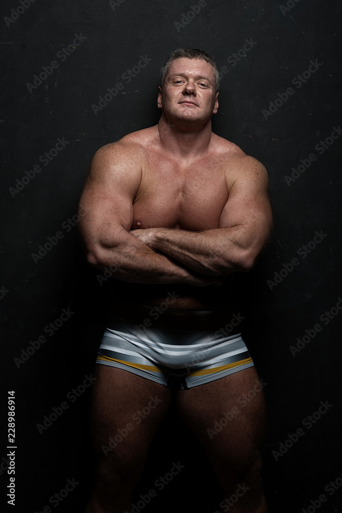 Fototapeta premium muscular man shows off his body near black grunge wall