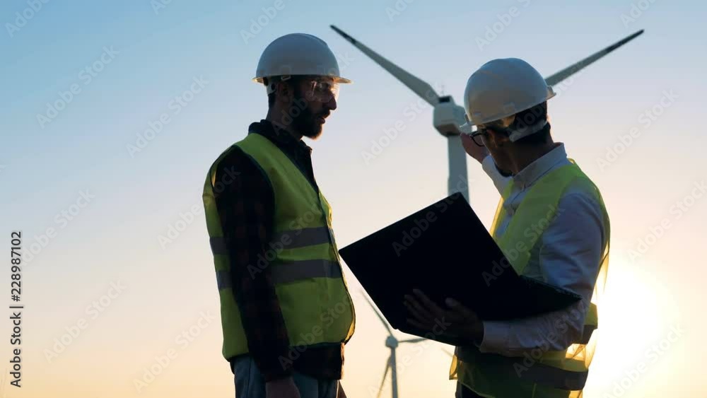 Male engineers working with a laptop on a field, close up.