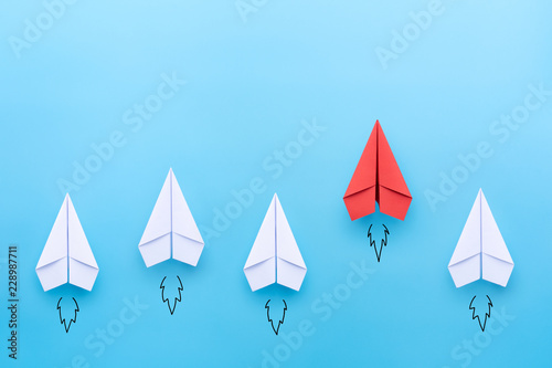 Red paper plane leading among a white planes on blue background. Business competition and Leadership concept photo