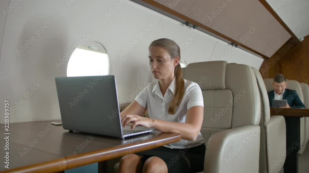Businesswoman using laptop on plane. She leaned back in the chair and look at window with relax. Luxury business deals during flight concept. Businesswoman using laptop on plane. She leaned back in the chair and look at window with relax. Luxury business deals during flight concept.