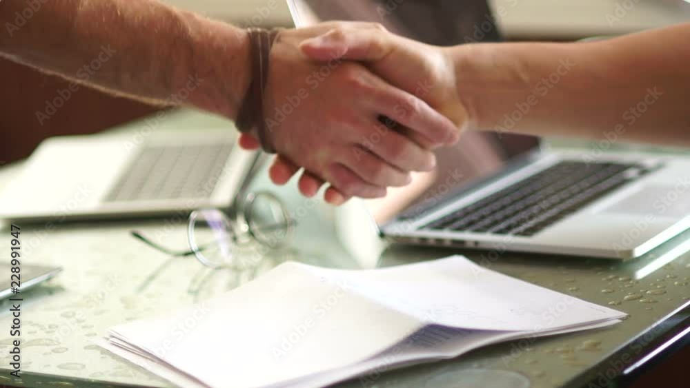 Close-up handshake of two businessmen. Men shake hands with each other. Business concept, deal, laptop on the table Close-up handshake of two businessmen. Men shake hands with each other. Business concept, deal, laptop on the table