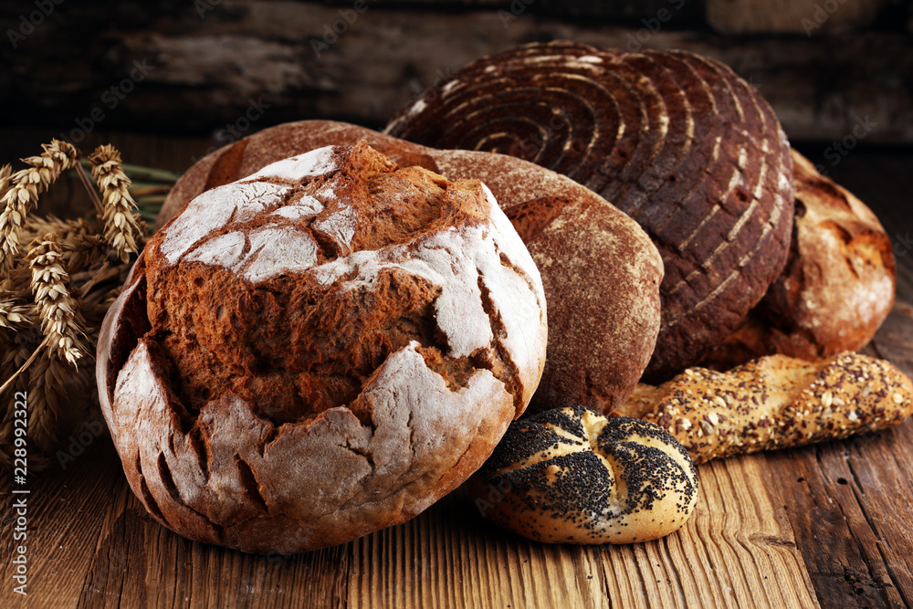 Fototapeta premium Different kinds of bread and bread rolls on board from above. Kitchen or bakery