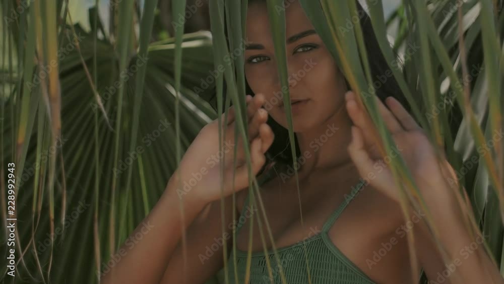 Beautiful girl posing in tropical forest. Luxury slow motion footage. Close-up of sensual young brunette mixed race Asian Caucasian woman wearing swimsuite with perfect tan wet hair looking out of Beautiful girl posing in tropical forest. Luxury slow motion footage. Close-up of sensual young brunette mixed race Asian Caucasian woman wearing swimsuite with perfect tan wet hair looking out of