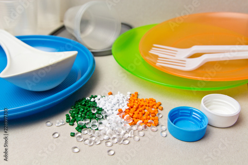 Plastic disposable tableware and Plastic Raw material. Colored granules of polyethylene, polypropylene. BPA FREE concept photo