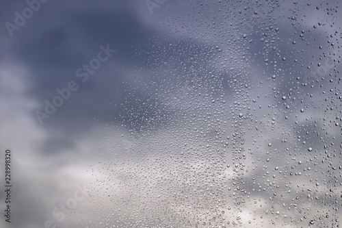 Rain / Water drop of rain on glass with blured blue sky background - sky afer rain.