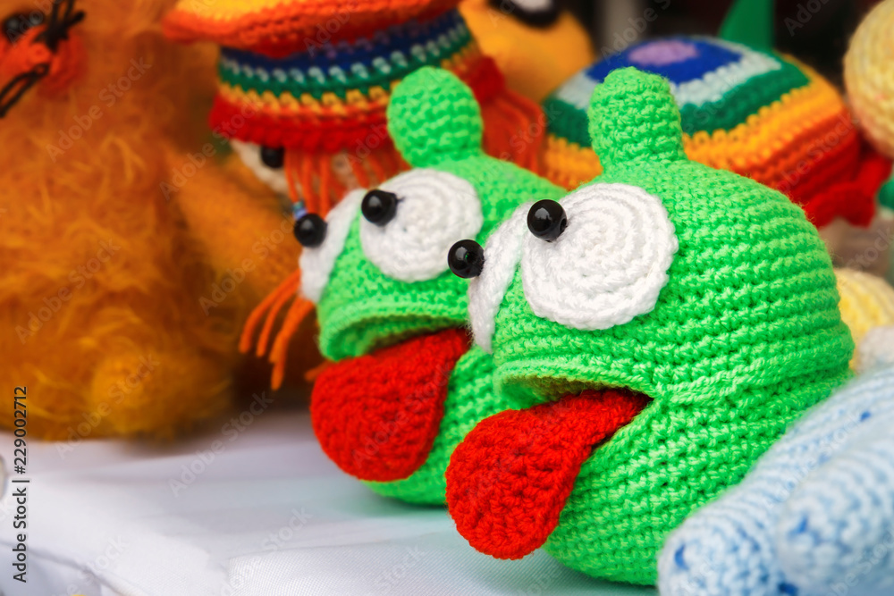 Colorful knitted handmade toys are on display for sale at a souvenir shop on the market. Close-up
