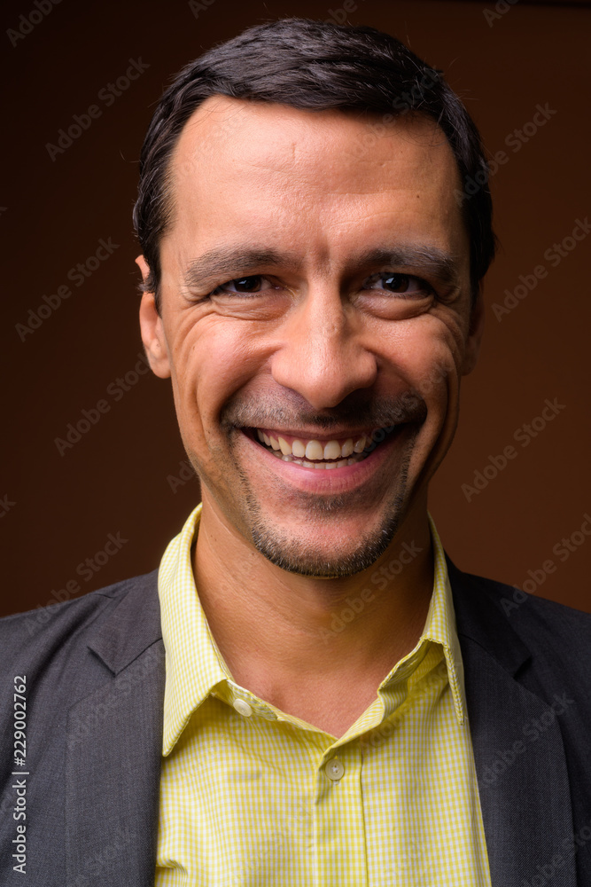 Face of handsome businessman smiling against brown background Face of handsome businessman smiling against brown background