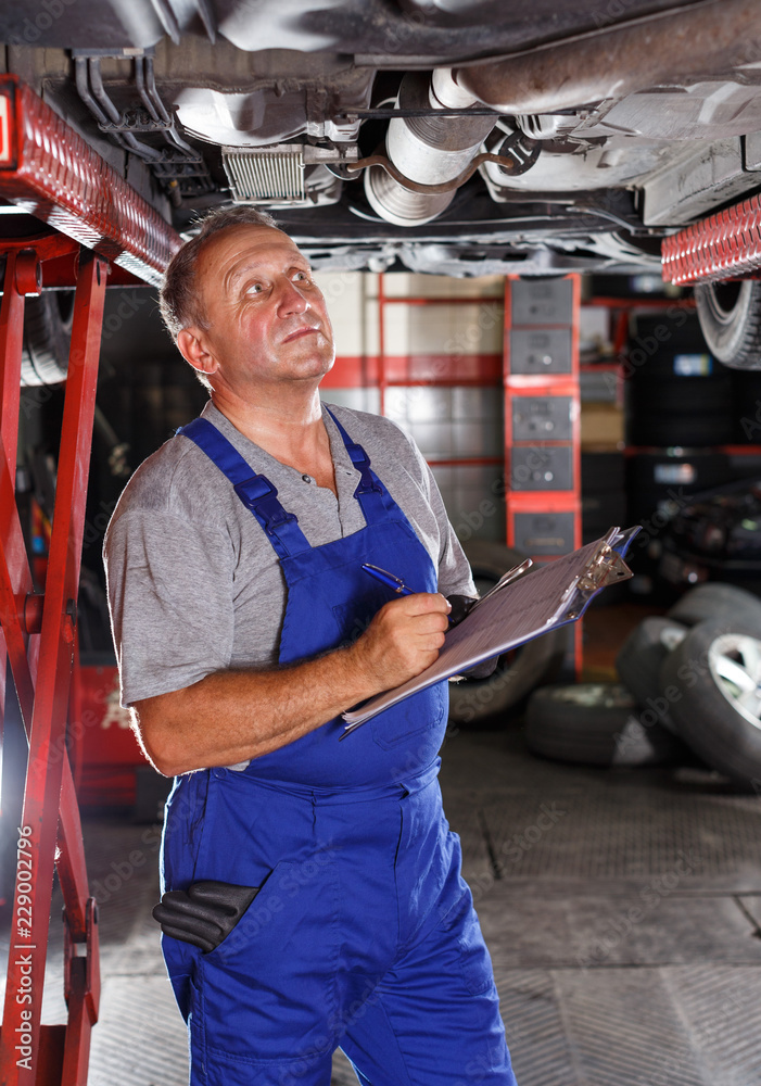Male mechanic taking notes about car repair