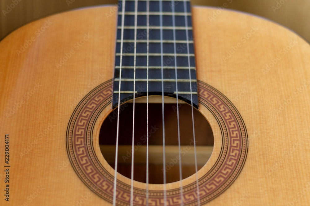 Concept to illustrate the guitar tutorials. Guitar body of natural wood, sound hole decorated with a pattern. Nylon strings go up the neck to the guitar head.