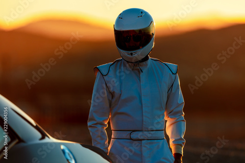A Helmet Wearing Race Car Driver In The Early Morning Sun Looking At His Car Before Starting © SIX60SIX