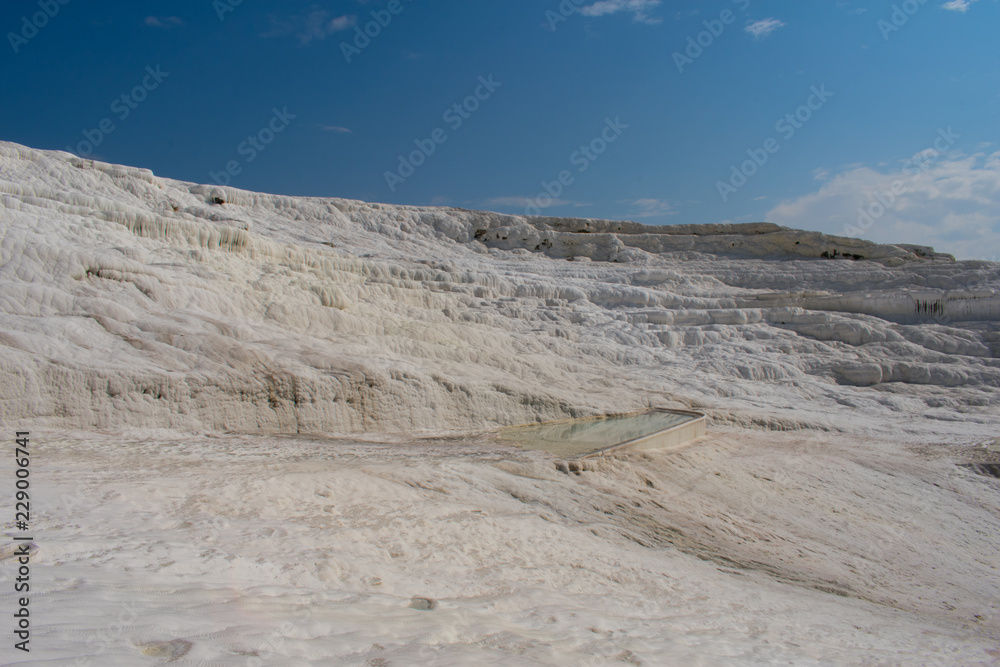 Sunny day in Pamukkale. Amazing white travertine, dry pool in Pamukkale, geological phenomenon, literally 