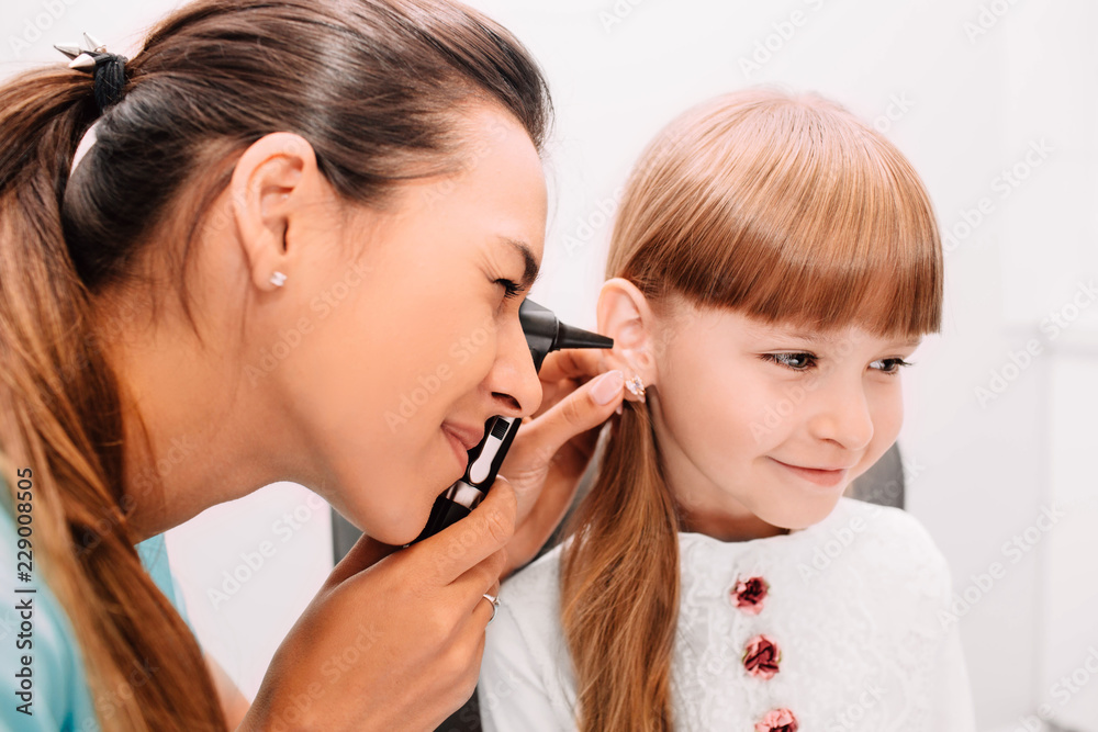 ENT doctor doing an ear exam with otoscope to little patient, close up ENT doctor doing an ear exam with otoscope to little patient, close up