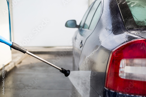 Shot of a man hands washing his car under high pressure water outdoors, cleaning concept photo