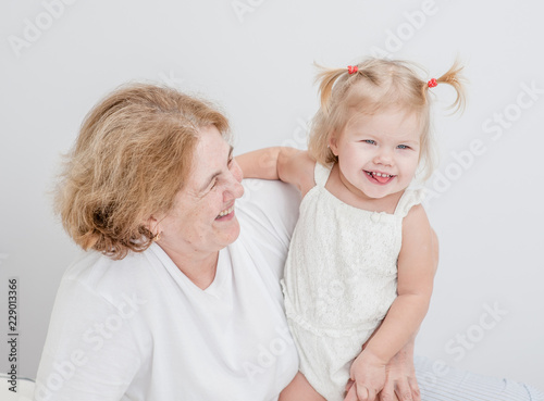 Grandmother and baby girl having fun on the bed