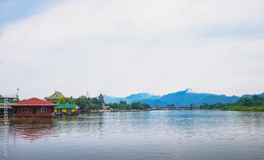 Fototapeta premium temple and community near the river with mountain background