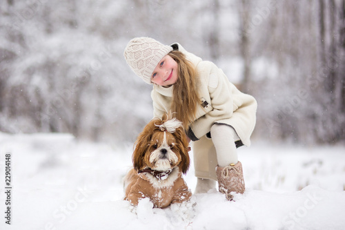 In winter, snow falls in the snowy forest,  little girl play with dog.