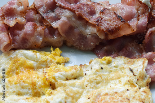 Bacon slices and fried eggs close up.