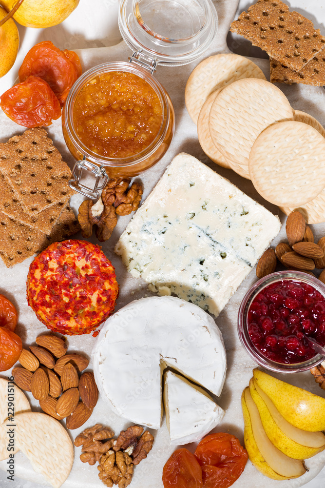 Fototapeta premium assortment of snacks with cheeses, fruits and nuts, top view vertical