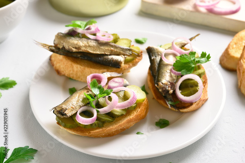 Sandwiches with sprats, marinated cucumber and onion