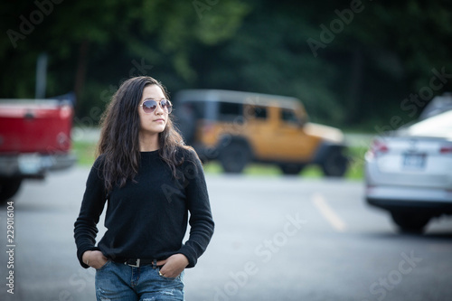 model girl standing in parking lot by vehicles