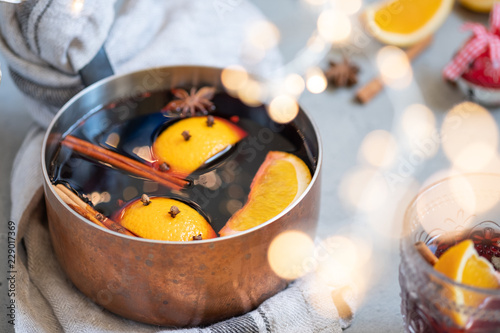 Fotografia, Obraz Mulled wine hot drink with oranges and spices in copper pot