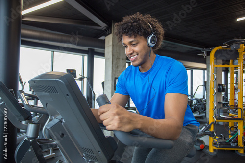 Handsome young african american man cycling at the gym