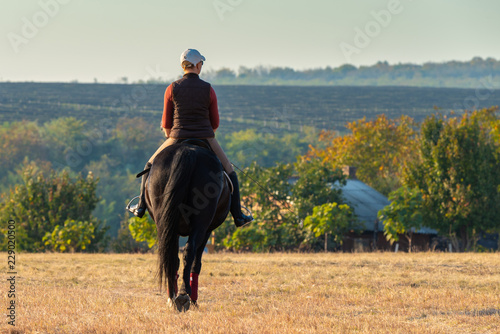 A beautiful woman rides a black horse on the hill, in autumn © blanke1973