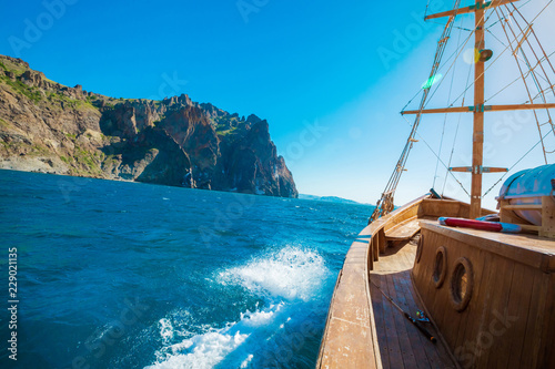 Wooden yacht. Vintage boat floating near the shore of a mountain. Fishing in the sea.