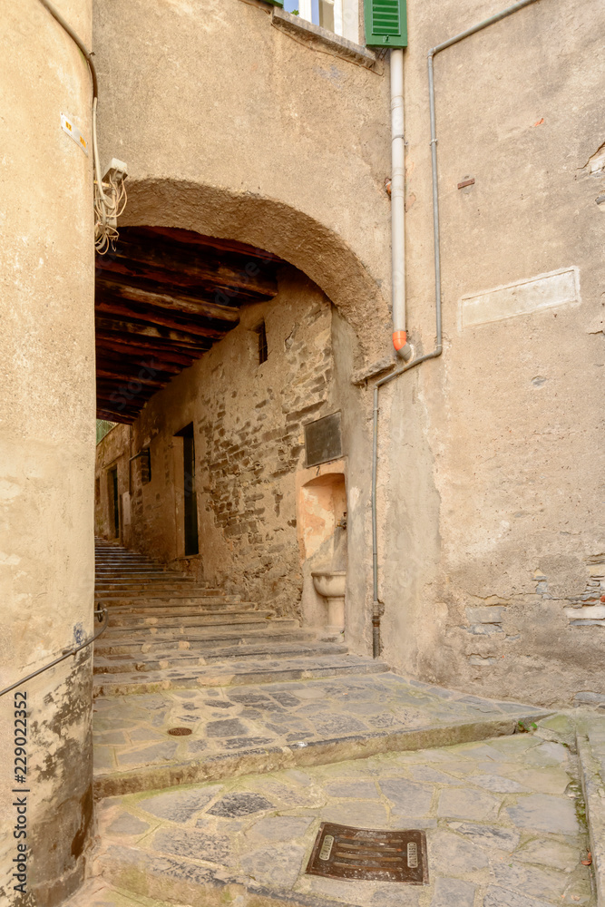 arched passage on narrow street with steps in village on Como lake, Moltrasio, Italy