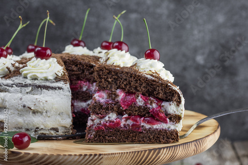 Detail on a Slice of a Black forest cake, or traditional austria schwarzwald cake from dark chocolate and sour cherries on wooden table.