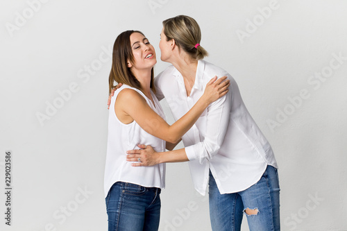 Happy friends are greeting and having fun at white background. Two beautiful young women © lukas_zb