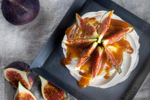 Top view on a meringue figs with whipped cream and caremel glaze on black tray. photo