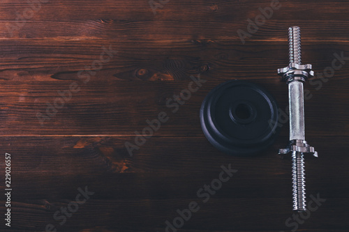 Iron dumbbell bar handle and plates on brown wooden table photo