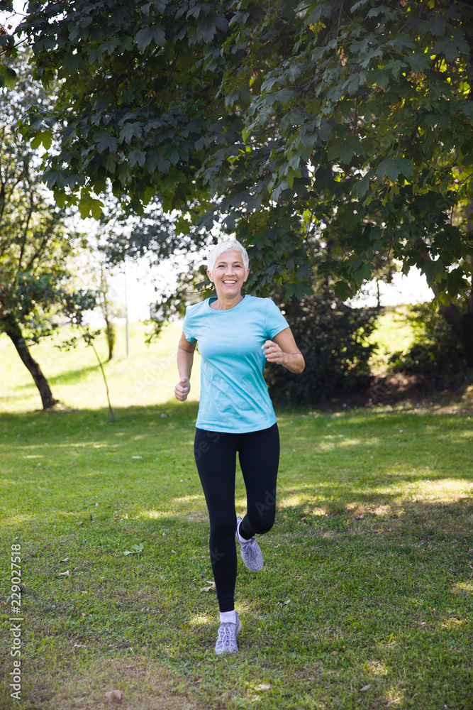 Senior woman jogging through park Senior woman jogging through park