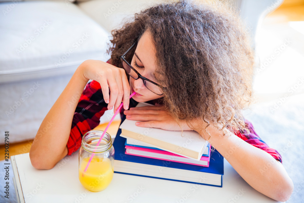 Fotografie Curly hair teen girl drinks juice and resting on books