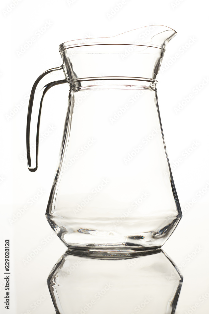 Empty pitcher for juice or milk. Isolated on white. Jug on reflective surface. Empty pitcher for juice or milk. Isolated on white. Jug on reflective surface.